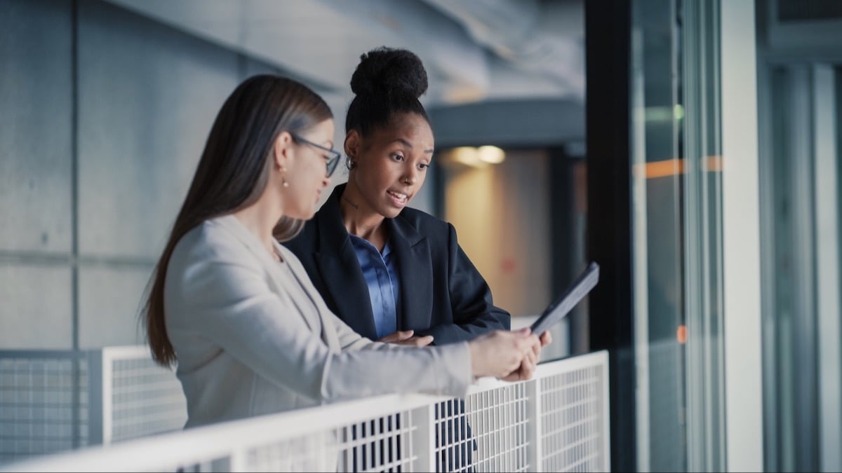 Two employees talk before an important meeting, showing how growing mid-market teams take on more handoffs, requests, and coordination.
