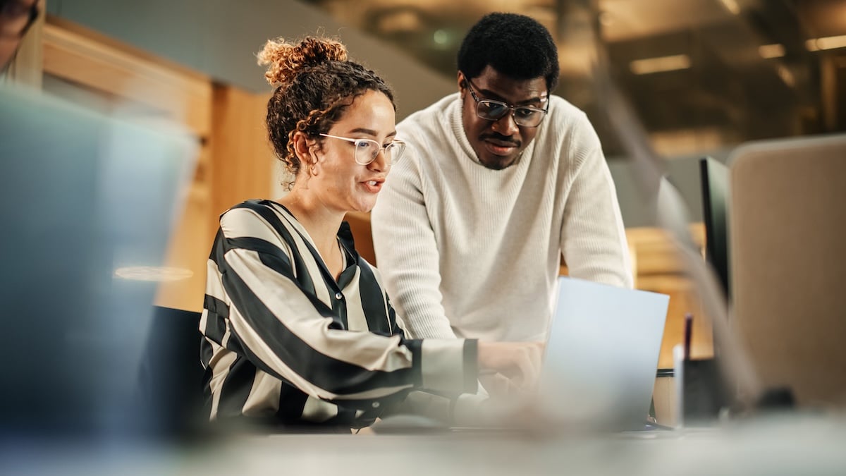 Two employees point at a laptop and talk through an AI roadmap, showing how Synergy Technical helps organizations decide where to start with AI agents.