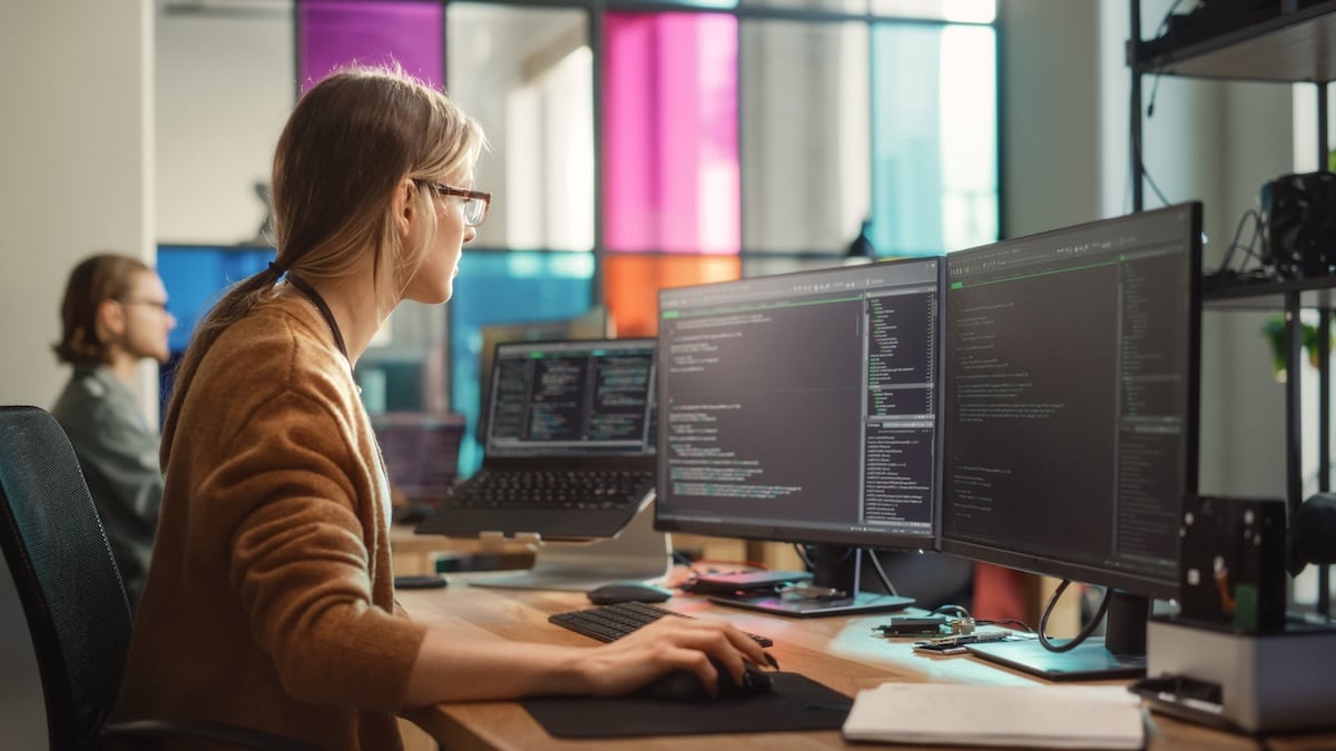 A woman with glasses reviews data and code on her screen, showing how AI agents can gather information and prepare work for review across departments.