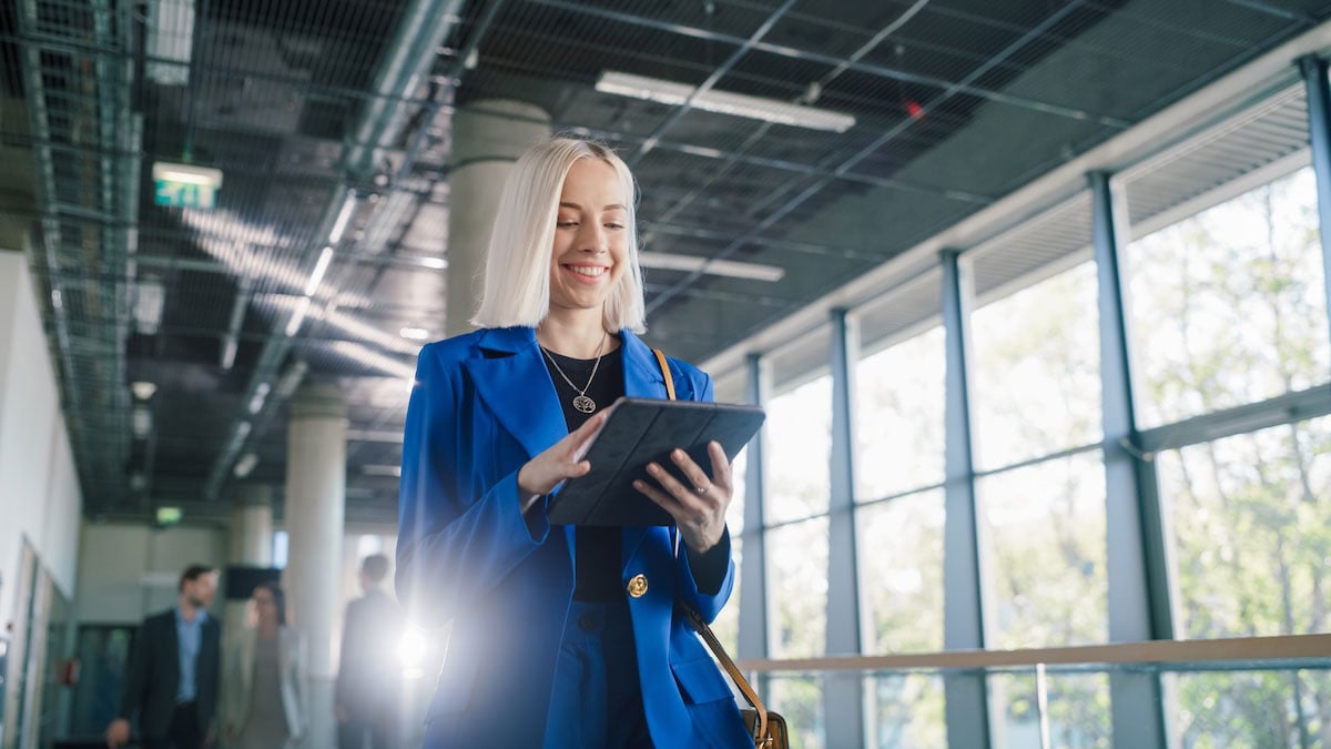 An agency executive reviews notes on her tablet between meetings, showing how AI workflows help leaders stay on top of commitments and priorities.