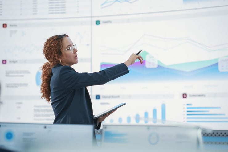 A data analyst reviewing dashboards and charts on multiple monitors, illustrating how a clear AI strategy aligns data, governance, and insights to drive measurable business outcomes.