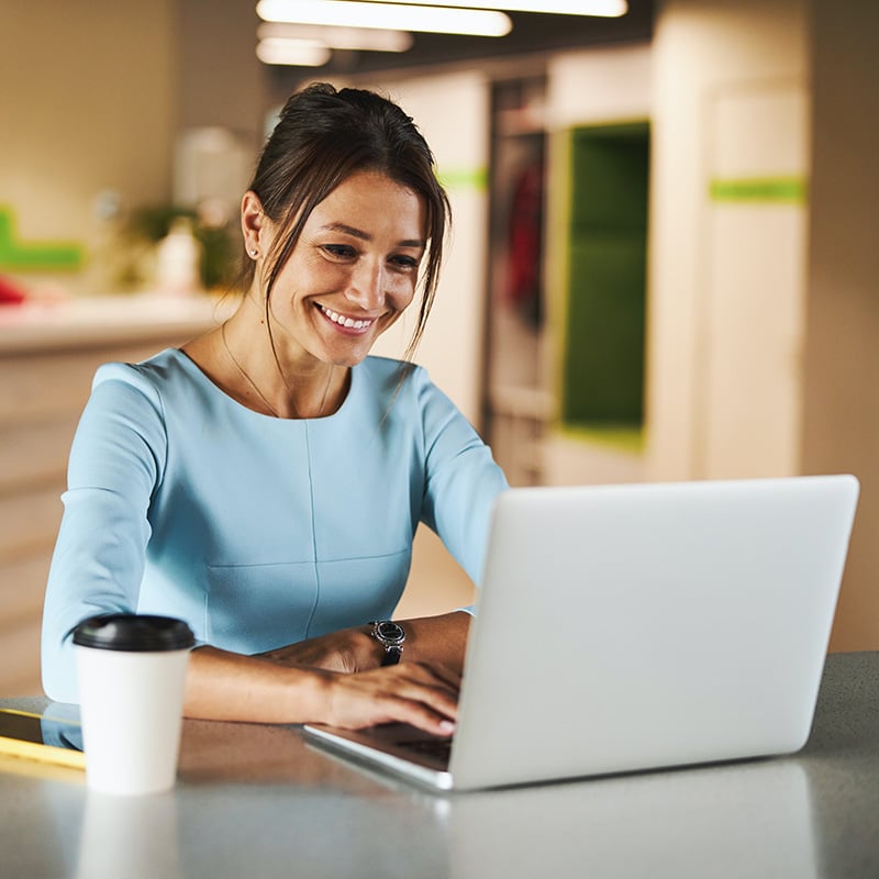 Picture of employee working in an office & using Copilot in PowerPoint to transform a text-heavy slide into clear and concise bullet points for enhanced clarity.