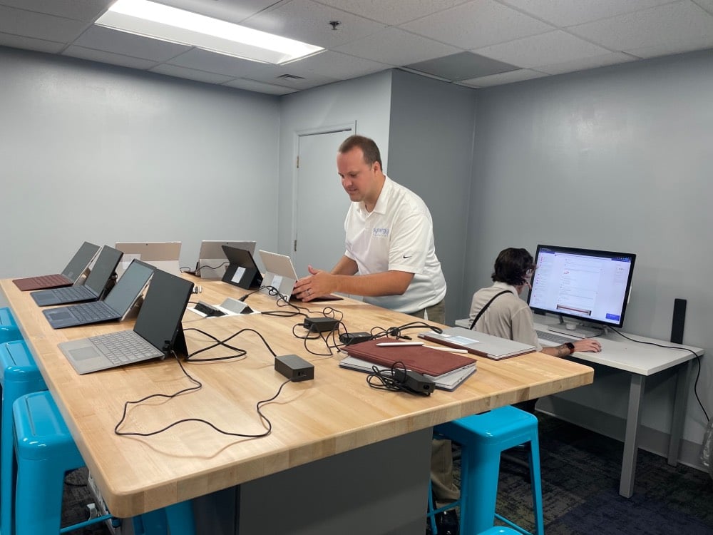 A picture of a Synergy Technical employee helping setup Surface devices for a nonprofit event