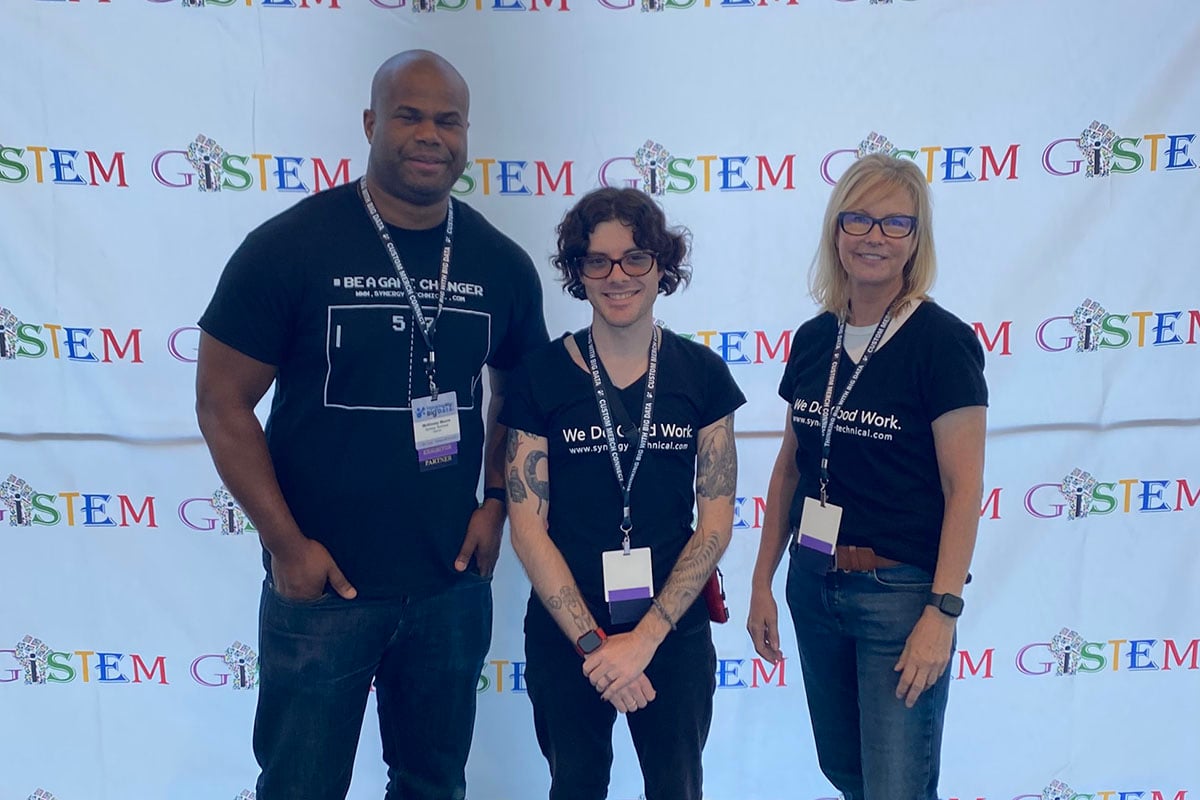 Picture of delivery team from Synergy Technical helping to deliver to students hands-on experience with coding, learning to create their own programs and apps at the GiSTEM event.