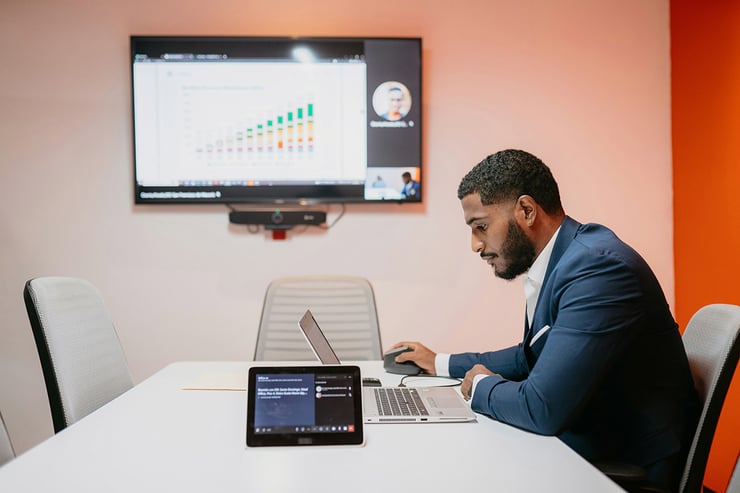 In a meeting room, a male analyst explains visualized trends using Fabric’s lake-centric architecture, which simplifies reporting across multiple data sources.