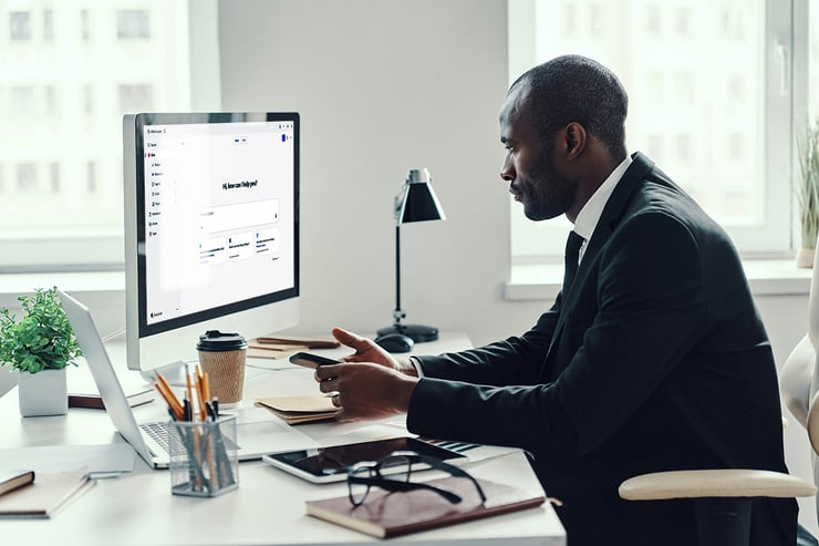 An IT leader sits at his desk reviewing analytics on his laptop, considering how a Microsoft Copilot strategy could streamline operations and support his company’s goals.