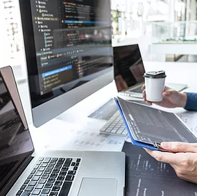 A hand holding a tablet next to a laptop illustrates how Microsoft Intune seamlessly integrates and secures multiple devices, providing users with flexible, secure access to work resources from anywhere.
