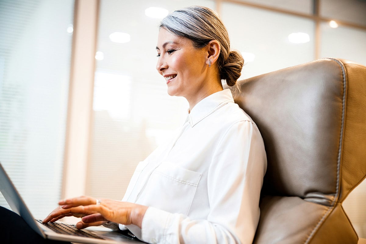 An executive, holding a work phone, accesses sensitive organizational data securely thanks to her company's robust cloud identity protections for all its end users.