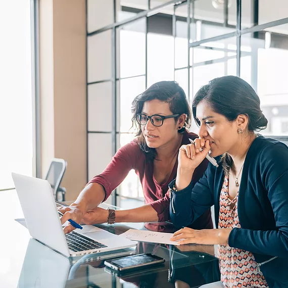Two employees sit together in a meeting room, using Microsoft 365 applications like Planner and Projects in Microsoft Teams to assign tasks and strategize content, with Microsoft Entra ID ensuring secure, role-based access, seamless authentication, and identity protection, allowing them to collaborate efficiently without security concerns.