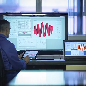 A data analytics employee analyzes charts and figures on a tablet, desktop, and laptop, all efficiently managed and secured by Microsoft Intune, ensuring seamless data synchronization, security, and compliance across multiple devices.