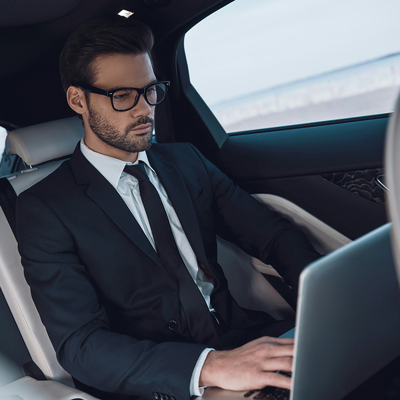 Picture of employee working on his laptop during his business trip and using Copilot in Outlook to reply to clients quickly and efficiently by drafting replies for him.