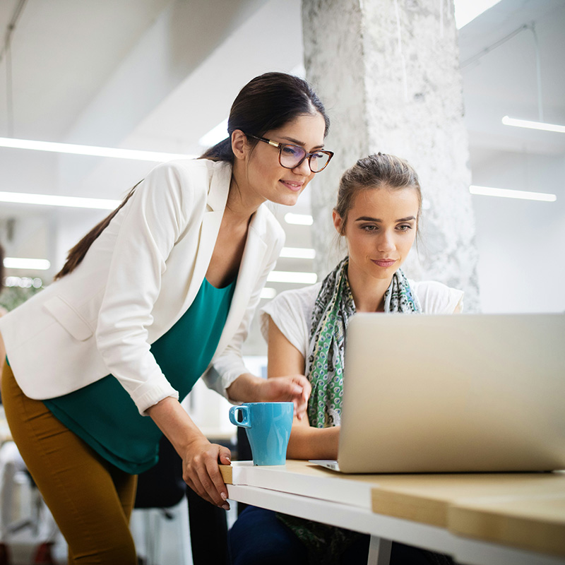 Two employees sit together in a meeting room, using Microsoft 365 applications like Planner and Projects in Microsoft Teams to assign tasks and strategize content, with Microsoft Entra ID ensuring secure, role-based access, seamless authentication, and identity protection, allowing them to collaborate efficiently without security concerns.