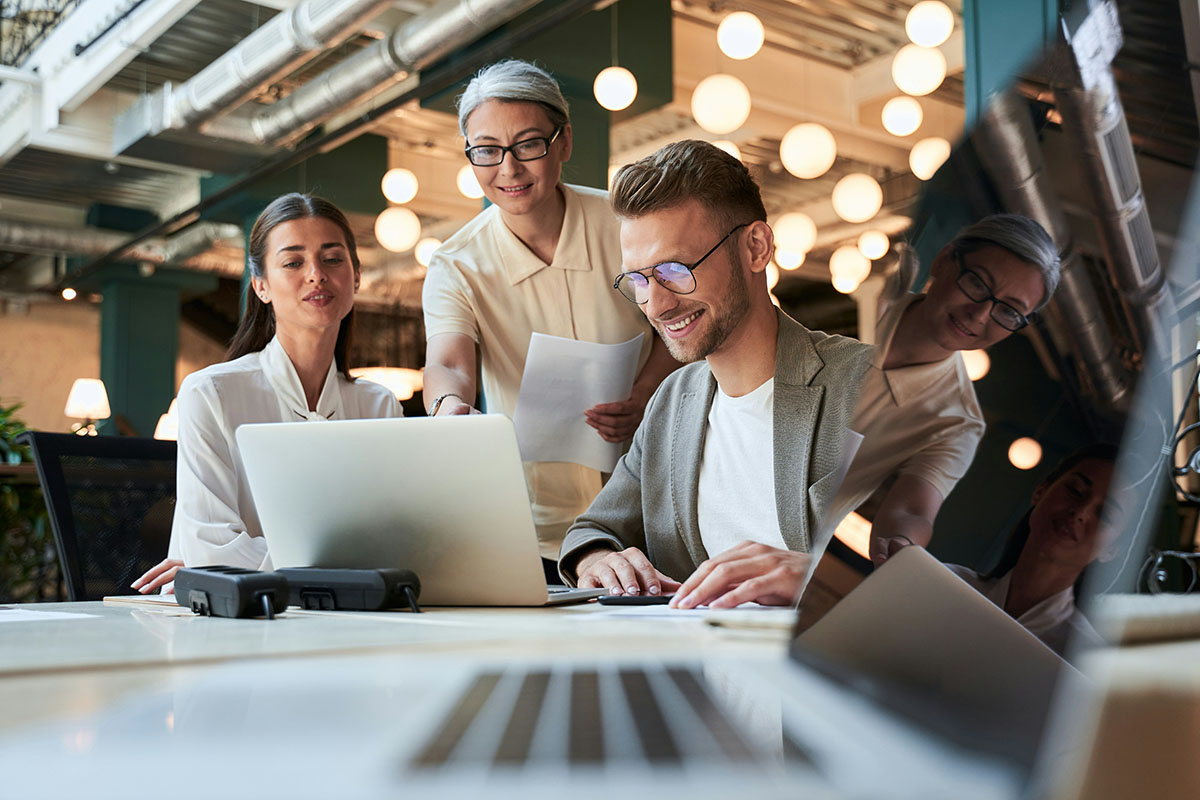 A facilitator from Synergy Technical points to a large touchscreen, demonstrating key Microsoft solutions to an attentive group of employees, guiding them through real-world scenarios that enhance collaboration and security.
