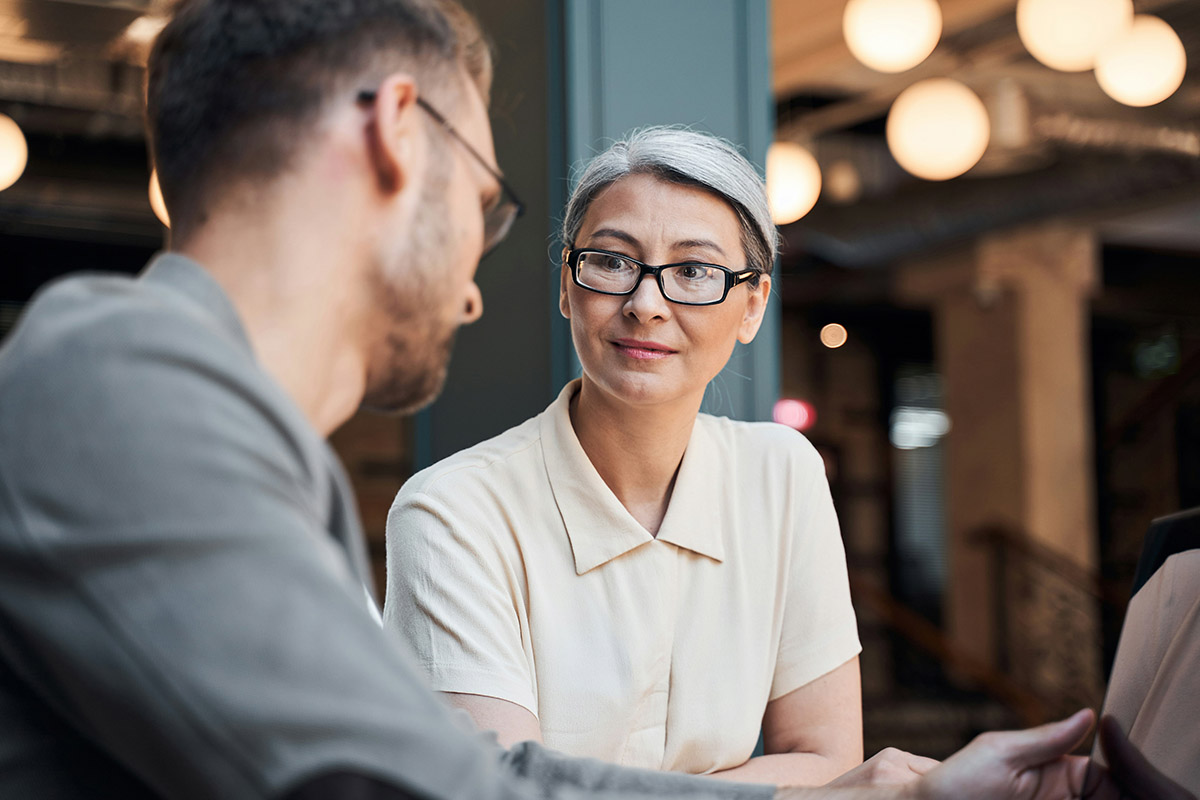 A group of employees sits in a conference room, fully engaged as a facilitator from Synergy Technical leads a Microsoft Security Workshop, helping them discover new ways to streamline workflows and boost productivity.