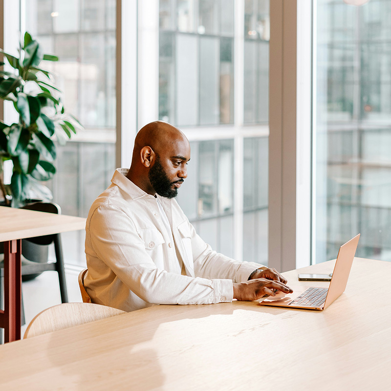 A male employee works undisturbed while compliance and security teams use Microsoft Purview Audit in the background to keep data secure without affecting productivity.