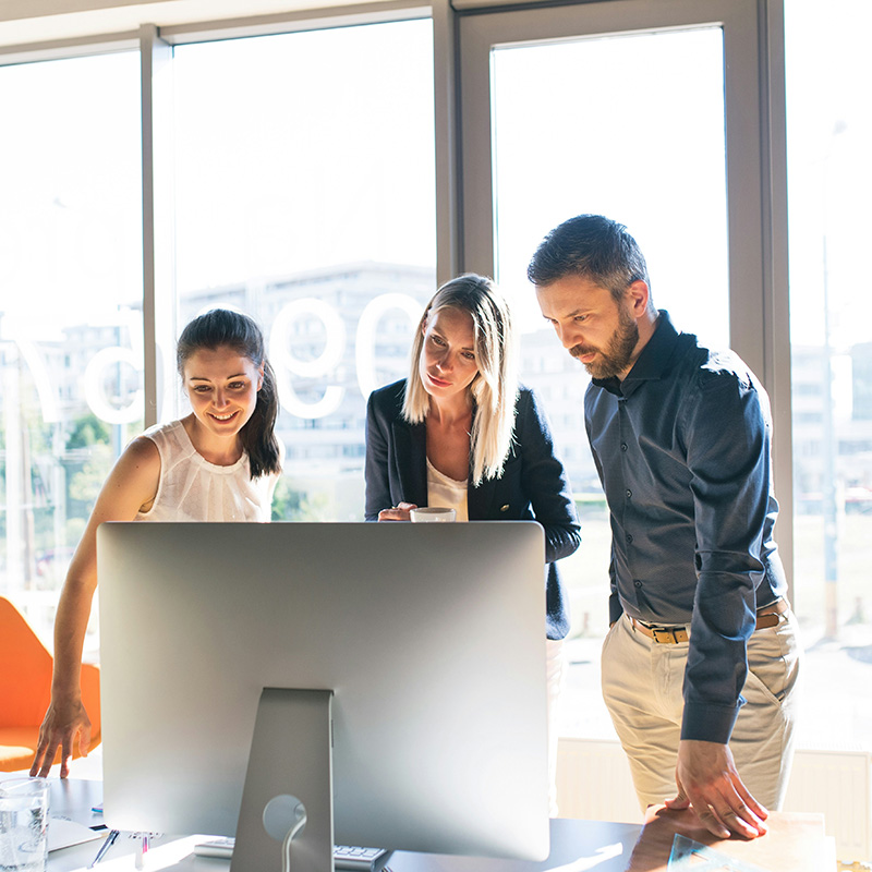 A team of employees works across SharePoint and OneDrive, unaware that Purview Data Lifecycle Management is automatically applying retention labels and managing data cleanup—so they can focus on their work without interruptions.