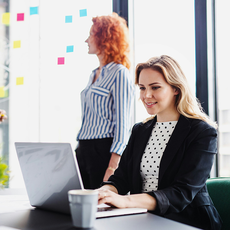 A female employee smiles as she works efficiently, knowing Microsoft Purview Information Protection keeps her data secure behind the scenes.