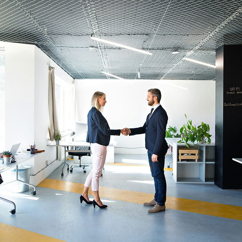 A senior HR employee and a compliance officer shake hands after successfully reviewing files placed on legal hold with Purview eDiscovery, confident that the process met compliance and legal standards.