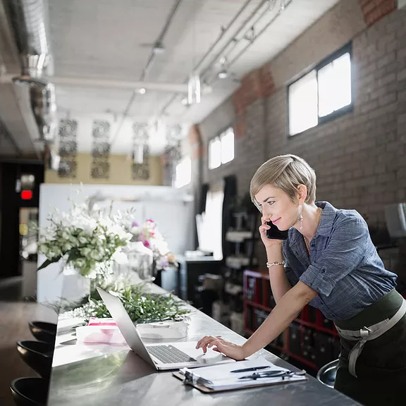 A female project manager communicates with her director via Microsoft Teams Phone on her work mobile device, effortlessly searching for Word documents in her OneDrive, showcasing how she stays connected with her files and folders from anywhere.