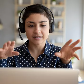 A female employee, animated and making hand gestures, passionately pitches her campaign idea during a Microsoft Teams meeting, with her team collaboratively reviewing shared OneDrive files to refine her brainstorm into actionable plans.