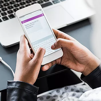 An employee sits at their desk, engaging with colleagues using Yammer in Microsoft 365 to foster networking and open, dynamic communication across the organization, strengthening connections and encouraging knowledge sharing in a more collaborative work environment.