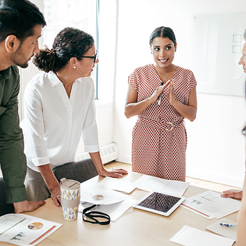 Two female business analysts meet to review reports and discuss key findings, with Microsoft Entra Conditional Access ensuring secure access to analytics platforms and data by applying real-time risk-based authentication, role-based permissions, and device compliance policies to protect sensitive business insights.