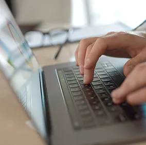 An employee sits at his desk, typing on his laptop while using Microsoft Teams in Microsoft 365 to seamlessly meet, chat, call, and collaborate with his team, staying productive and engaged no matter where he’s working.